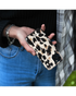 Hand met Samsung Galaxy A55 in Mio Leopard hoesje met glanzende panterprint.