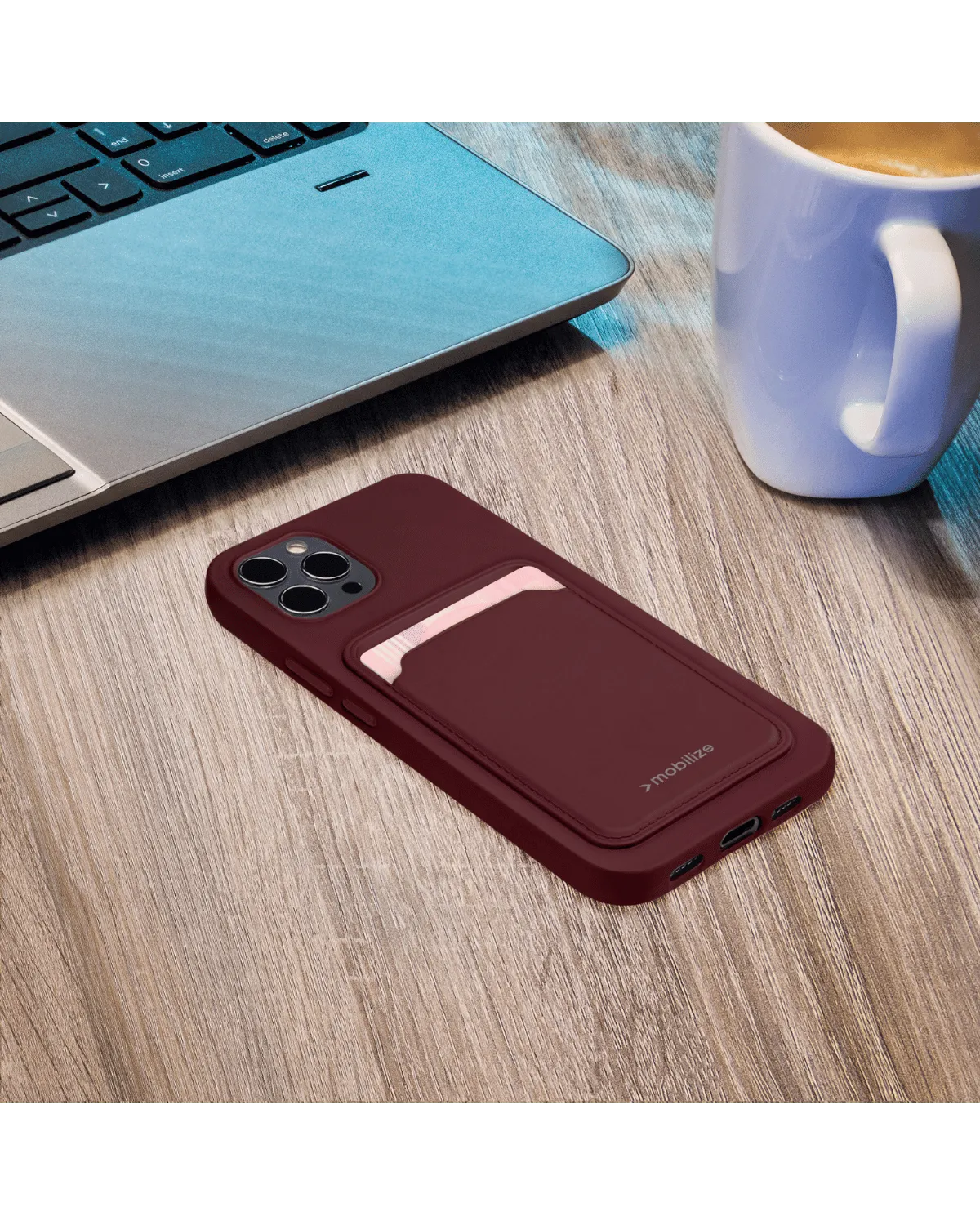 Mobilize Rubber Gelly Card Case in mat bordeauxrood met kaarthouder, liggend op een houten tafel bij een laptop.